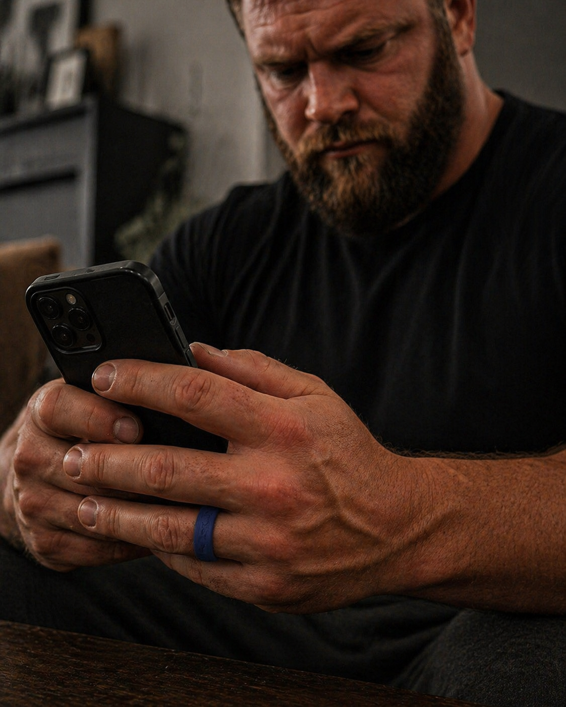 Man wearing Dura Gear blue silicone ring while using smartphone at home, durable flexible ring for everyday wear and comfort