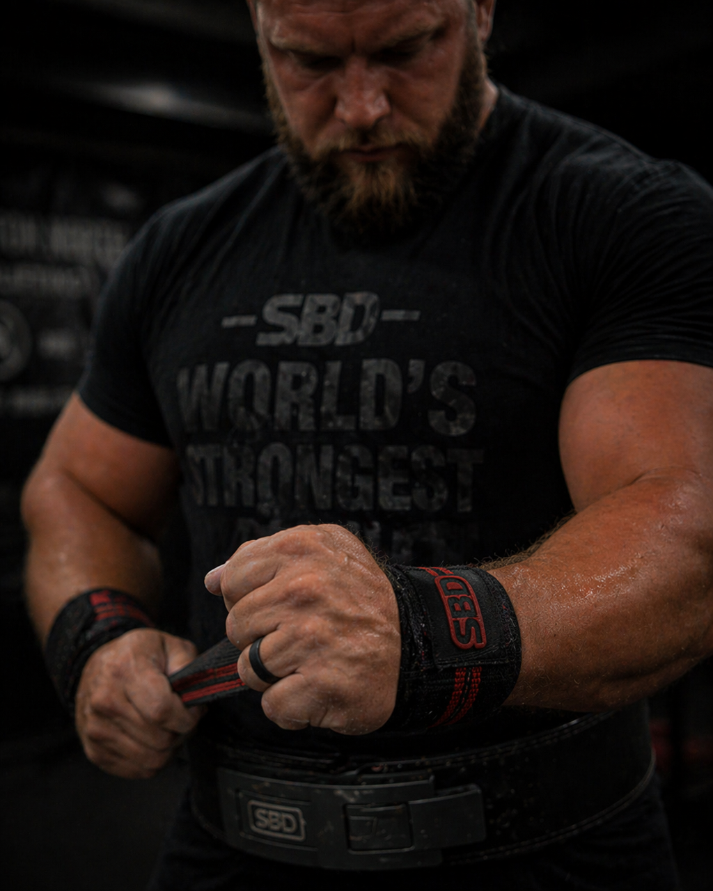 Close-up of a man tightening wrist wraps in the gym while wearing a black DuraGear silicone ring, highlighting comfort and flexibility during training.