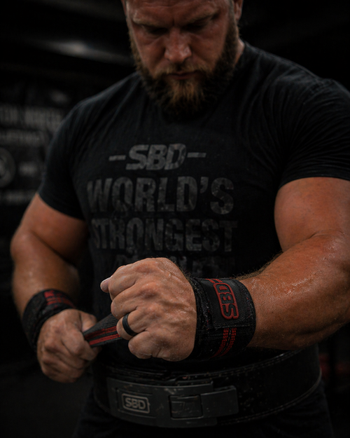 Close-up of a man tightening wrist wraps in the gym while wearing a black DuraGear silicone ring, highlighting comfort and flexibility during training.